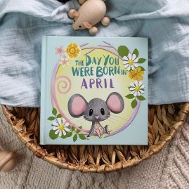 The book cover for Day You Were Born In April. A playful, illustrated mouse sat down surrounded by daffodils and daisies.