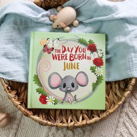 The book cover for Day You Were Born In June. A playful, illustrated mouse sat down surrounded by roses, daisies, and butterflies.